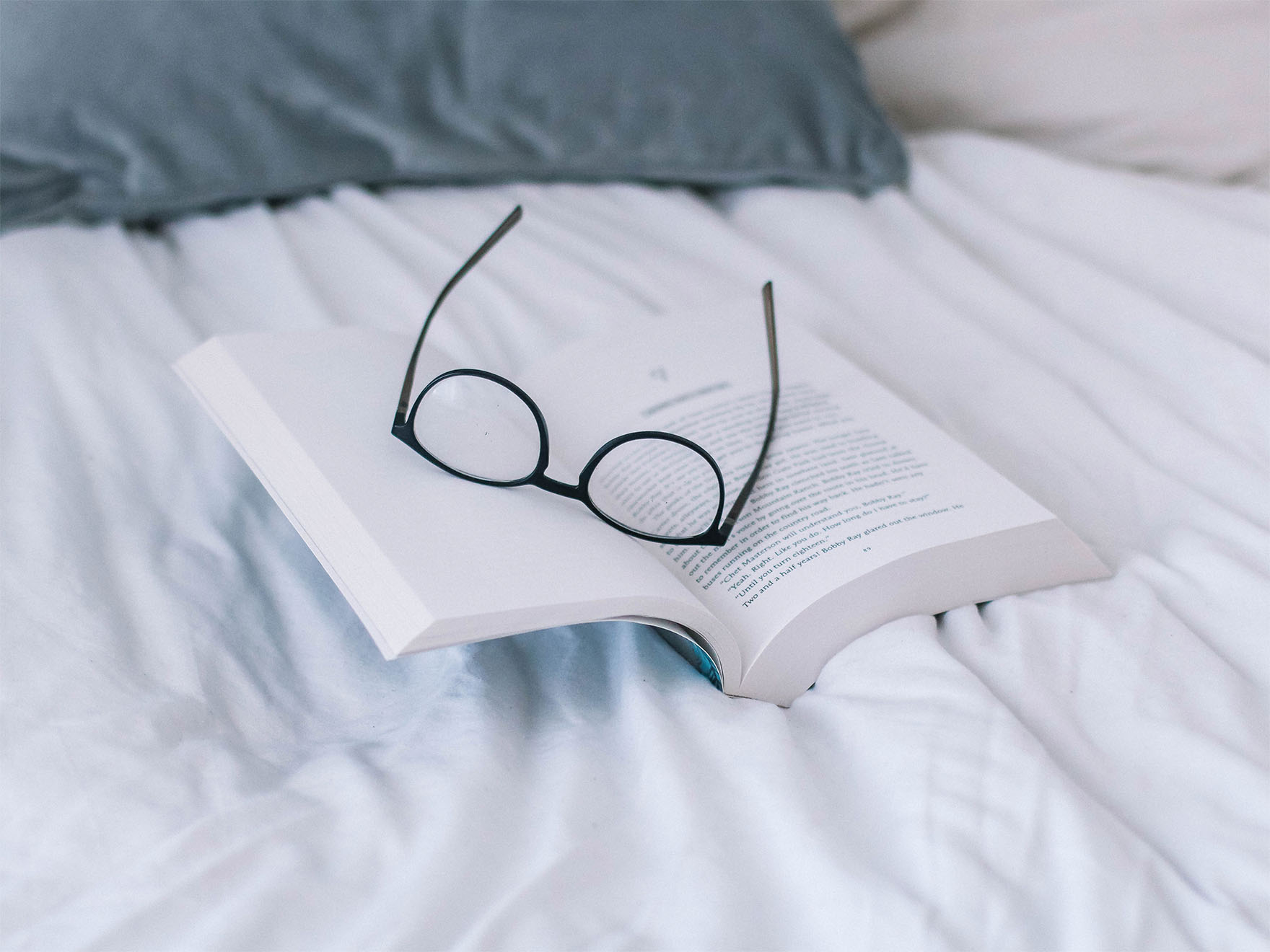 pair-of-glasses-on-a-book-on-a-bed