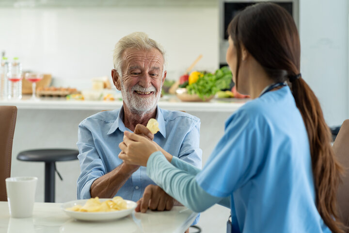 old man with carer eating crisps