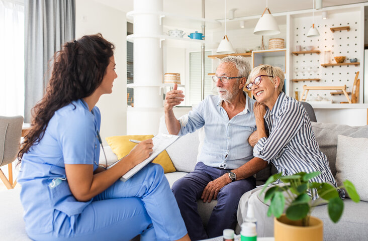 couple taking about care to a nurse on a visit